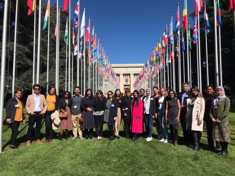 Group picture at Geneva excursion in front of the building, framed by national flags.