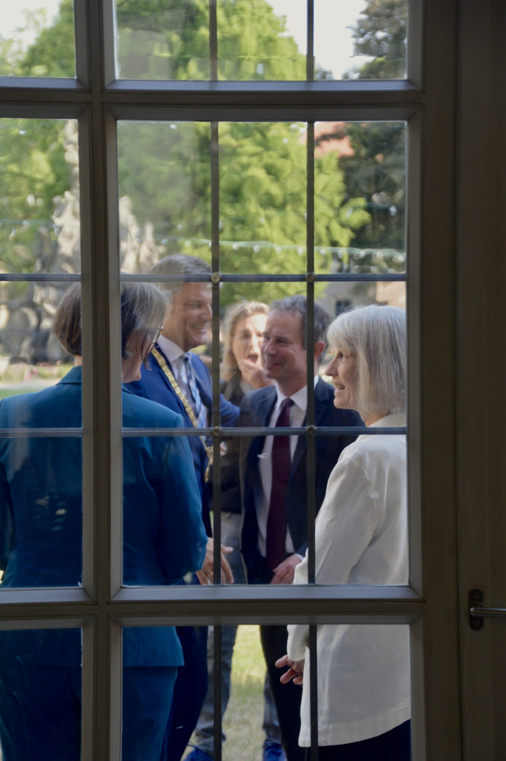 Picture of greetings between FAU Professors Kathrin Kinzelbach, Markus Krajewski, FAU president Joachim Hornegger and Kathryn Sikkink through windowpane.