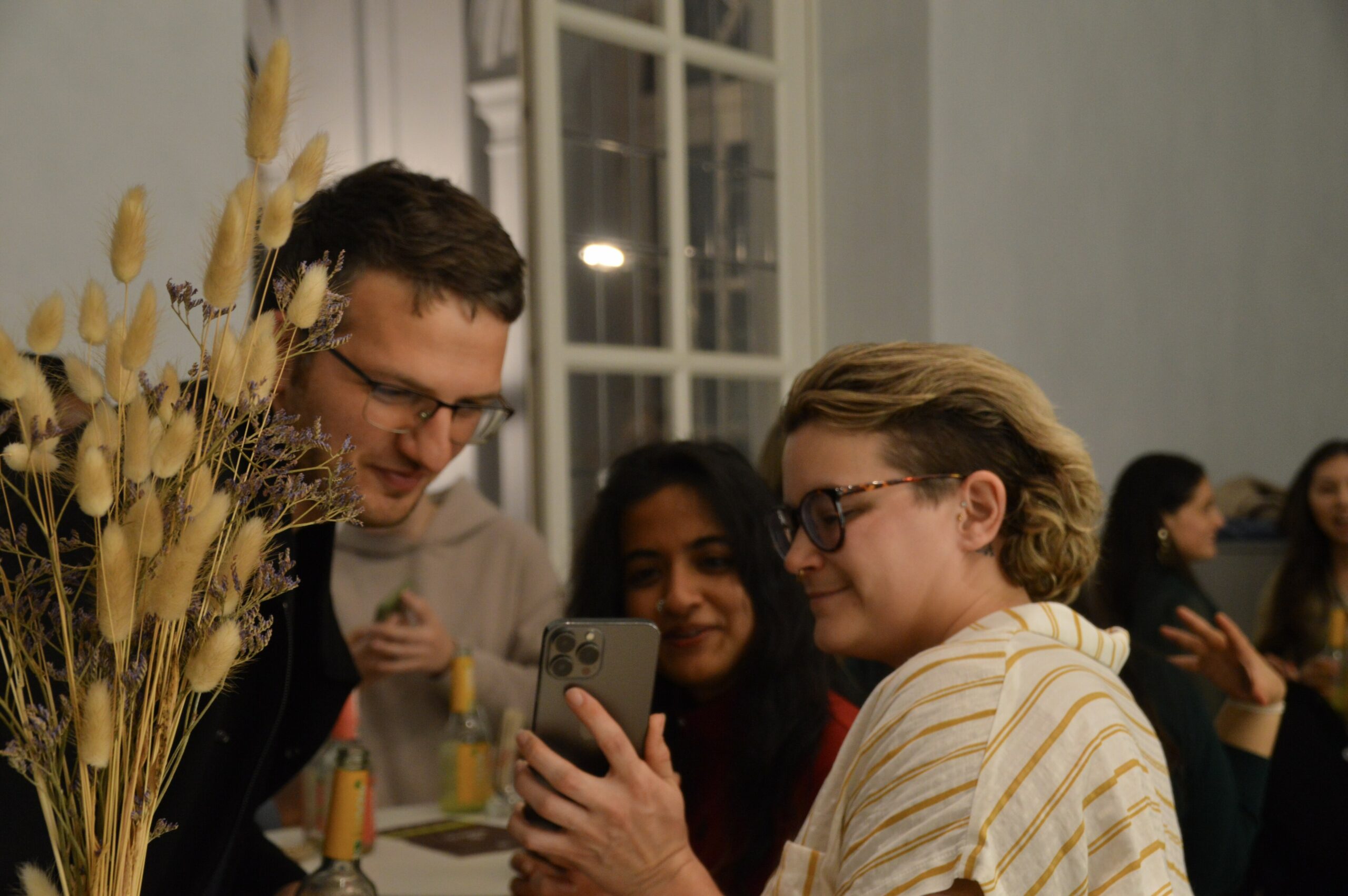 Reception after ceremony, three people chatting and looking at picture on one's phone