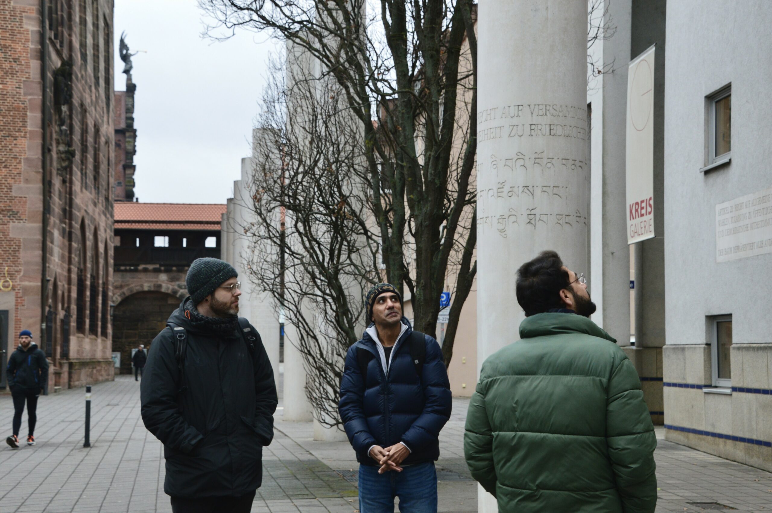 Tour guide and two MA Human Rights students reading the articles engraved into the collar on the "Way of Human Rights"